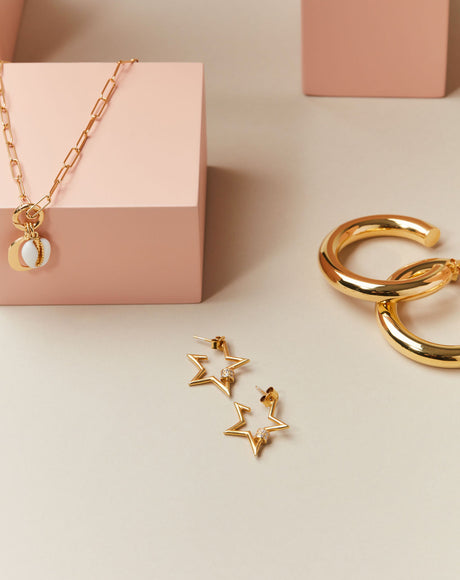 Styled product photography of the Stella Earrings, the Ciambella Gold Large Hoops, and the Piccolo Rimini Chain. 