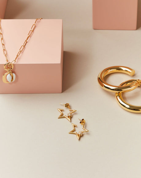Styled product photography of the Stella Earrings, the Ciambella Gold Large Hoops, and the Piccolo Rimini Chain.